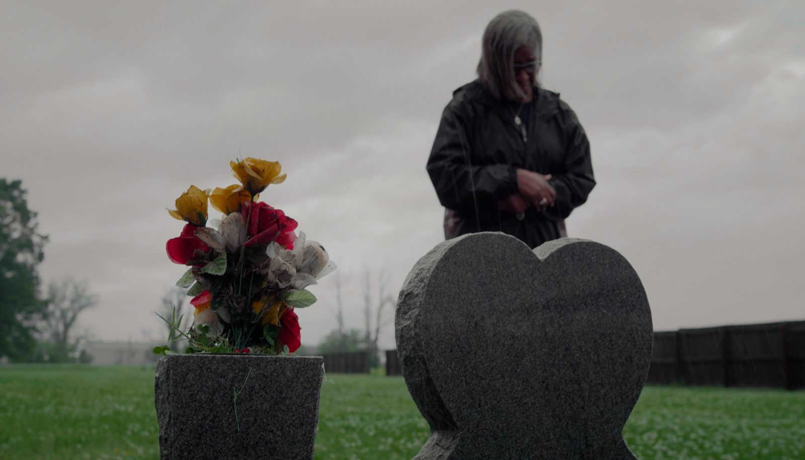 Carla at the gravestone of her husband, who passed away from COVID-19