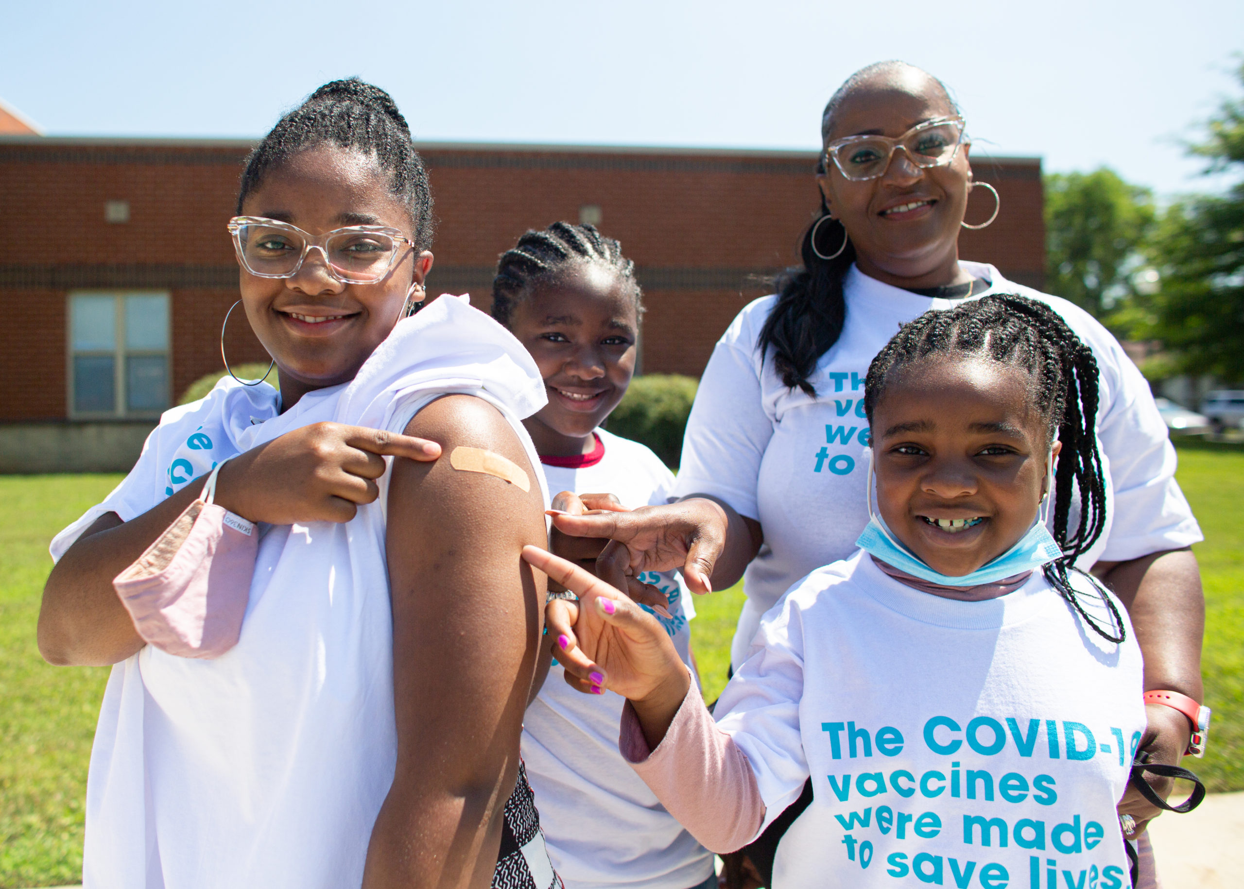 Young girl posing with her family after receiving a COVID-19 vaccine.